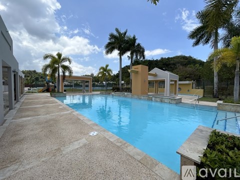 A large outdoor swimming pool surrounded by palm trees and a building.