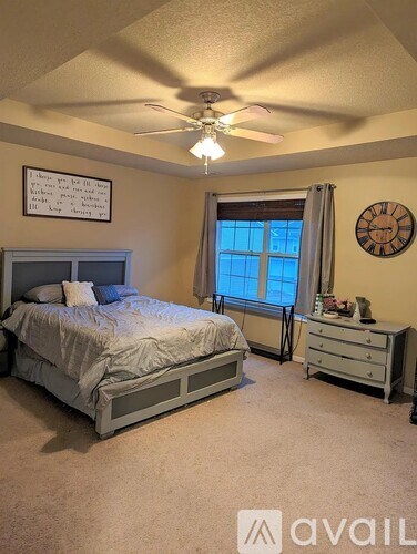 A bedroom with a bed, dresser, and window.