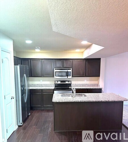 A kitchen with a refrigerator, oven, and sink.