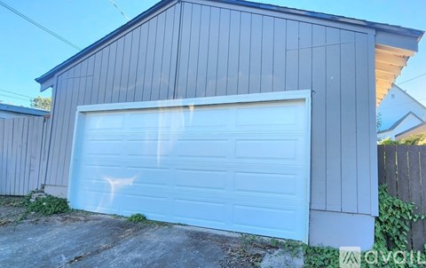 A white garage door is closed and appears to be made of metal.