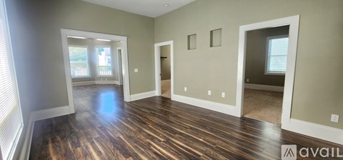 A spacious room with wood flooring and a large window.
