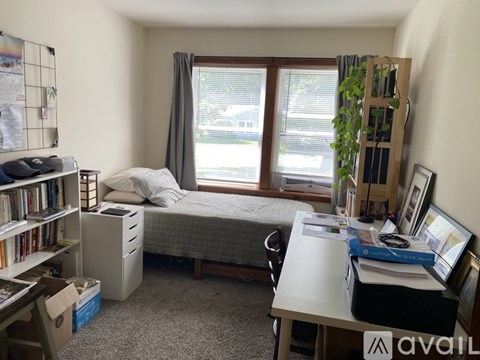 A bedroom with a bed, desk, and bookshelf.