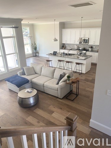 A living room with a white couch and a wooden floor.
