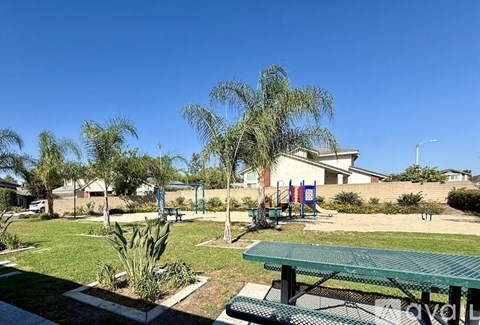 A park with a green bench and a playground in the background.