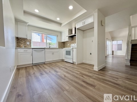 A spacious kitchen with wooden flooring and white cabinets.