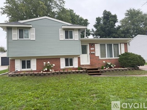 A house with a grey roof and red brick walls is for sale.