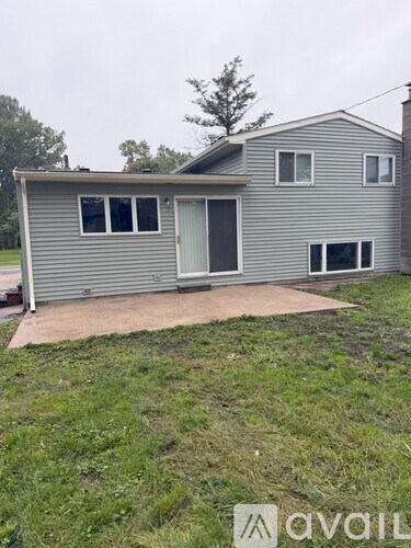 A house with a grey siding and a white door is available for rent.