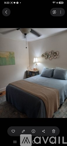 A bedroom with a bed covered in a blue sheet and a ceiling fan.