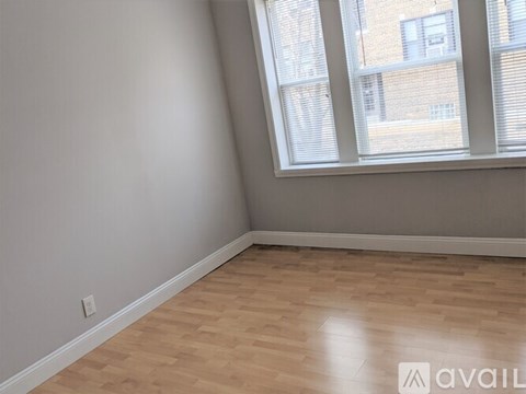 A room with wooden flooring and a window with blinds.