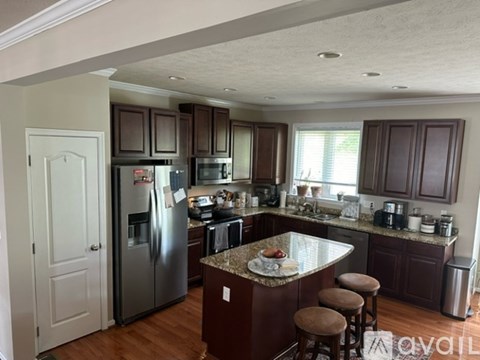 A kitchen with a refrigerator, microwave, oven, and sink.