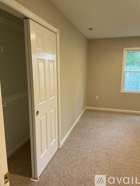 A white door is open to a carpeted room with a window.