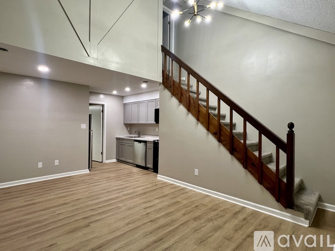 A room with wooden floors and a staircase leading to the upper level.