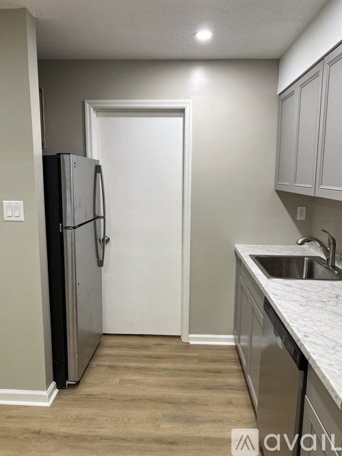 A kitchen with a refrigerator, sink, and cabinets.