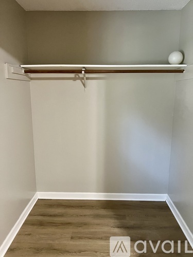 A room with a wooden floor and a white wall with a shelf and a ball on it.