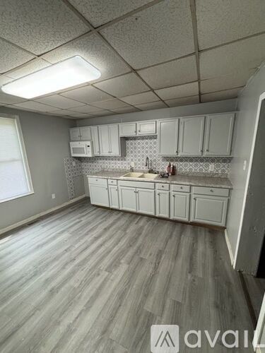 A kitchen with white cabinets and a wooden floor.