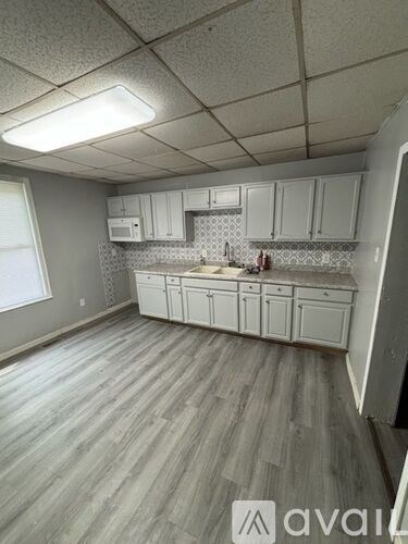A kitchen with white cabinets and a wooden floor.