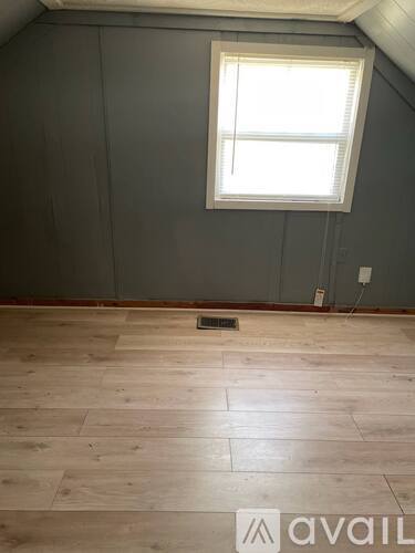 A room with a window and wooden flooring.