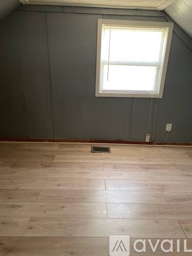 A room with a window and wooden flooring.