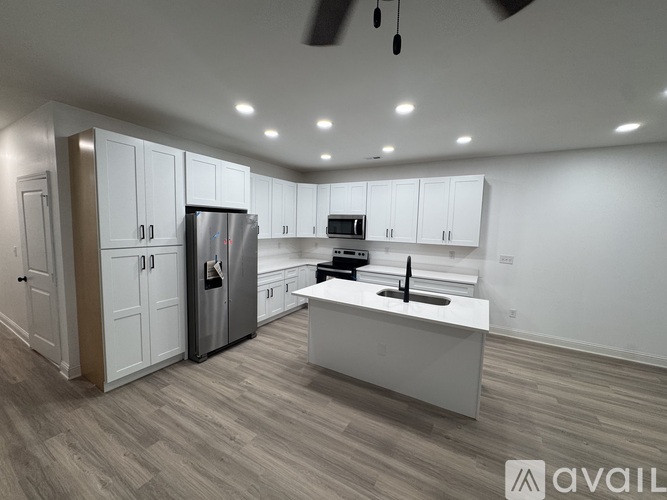 A modern kitchen with white cabinets and a wooden floor.
