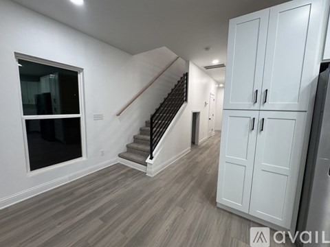 A spacious room with a staircase and a cabinet.