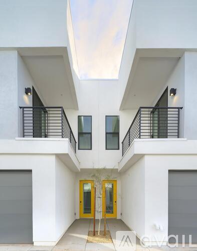 A white building with a yellow door and a skylight above it.