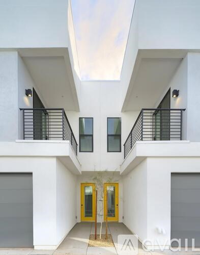 A white building with a yellow door and a skylight above it.