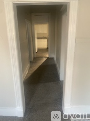 A hallway with white walls and a carpeted floor.