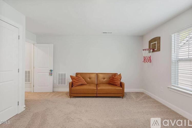 A living room with a brown couch and a basketball hoop on the wall.
