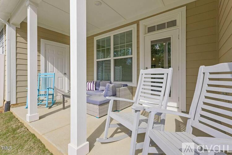 A porch with two white chairs and a blue chair.