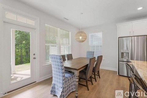 A dining room with a wooden table and chairs with a patterned cushion.