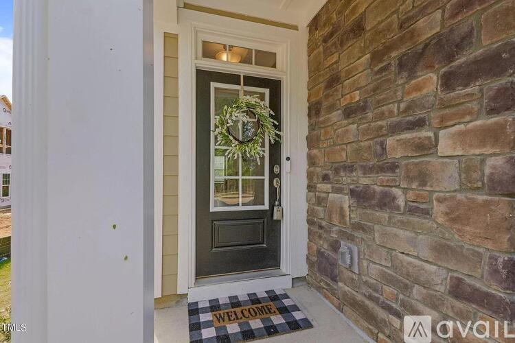 A house entrance with a black door and a welcome mat.