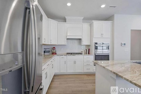 A modern kitchen with white cabinets and stainless steel appliances.