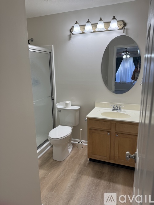 A bathroom with a toilet, sink, and mirror.