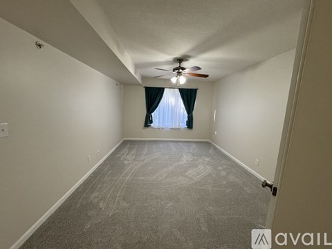 A room with a ceiling fan and a window with curtains.