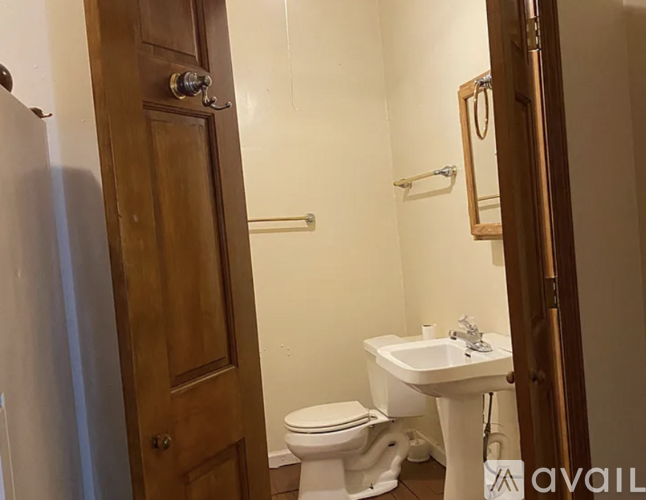 A bathroom with a toilet, sink and mirror.