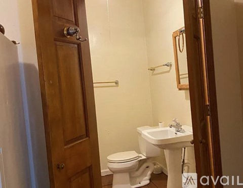 A bathroom with a toilet, sink and mirror.