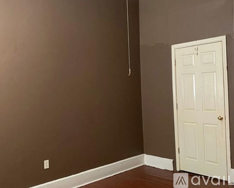A room with a white door and a brown wall.
