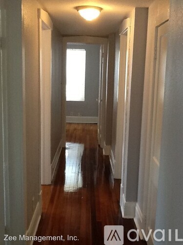 A long hallway with wood floors and white walls.