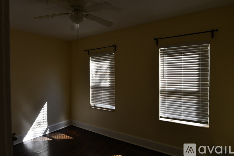A room with a ceiling fan and two windows with blinds.