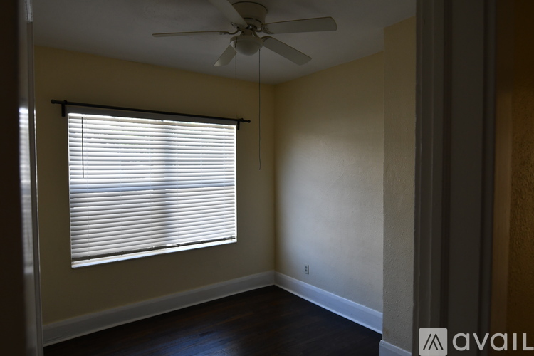 A room with a ceiling fan and a window with blinds.