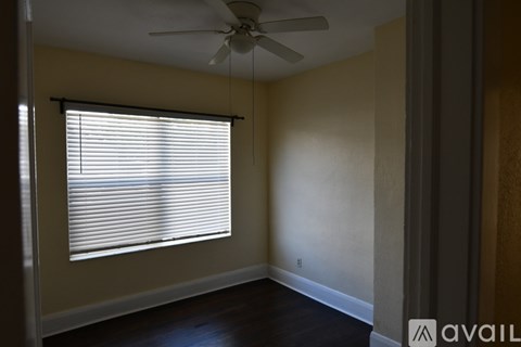 A room with a ceiling fan and a window with blinds.