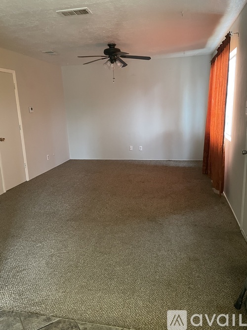 A room with a carpeted floor and a ceiling fan.