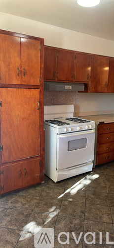 A kitchen with wooden cabinets and a stove with a white tile floor.