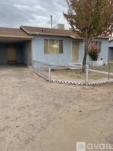 A house with a fence and a tree in front of it.