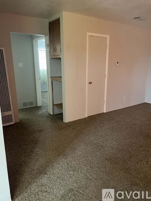 A room with a carpeted floor and two doors.