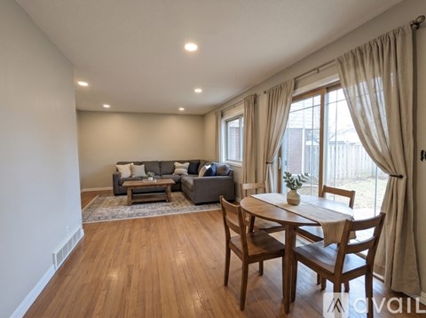 A living room with a grey couch, a wooden table and chairs, and a rug.