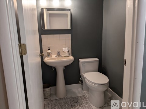 A bathroom with a sink, toilet and mirror.