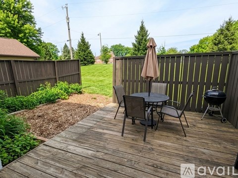 A wooden deck with a table and chairs and a grill.