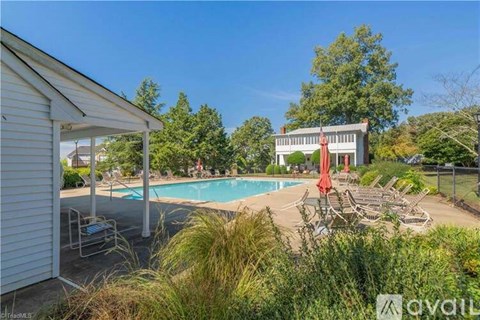 A pool area with a building in the background and a red umbrella.