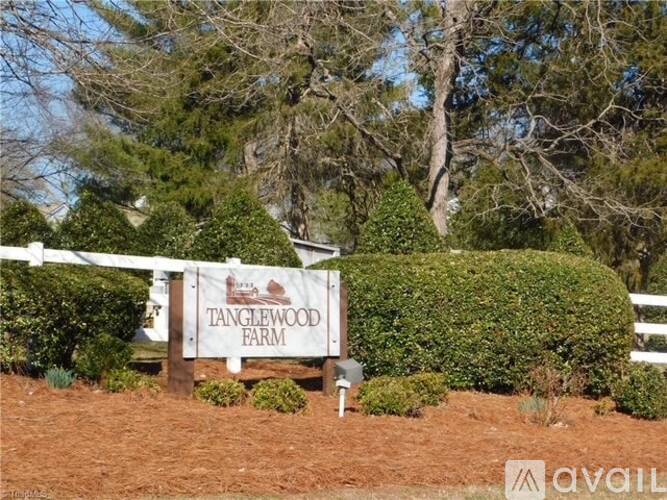A sign that says Tanglewood Farm is in front of a white fence.